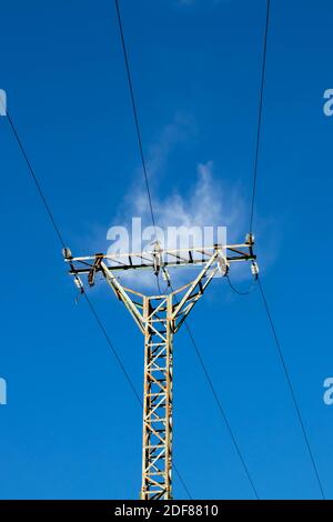 Power line pilon. Energy transmission and distribution. High voltage overhead electric line. Clear blue sky. Stock Photo