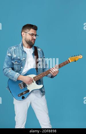 handsome man in denim with guitar isolated on blue background Stock Photo
