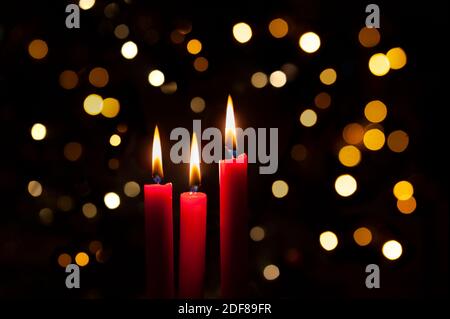 Three red  lit candles with colorful bokeh background Stock Photo