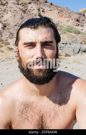 young man with wet hair after a bath on the beach wears sunglasses in casual style Stock Photo