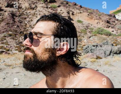 young man with wet hair after a bath on the beach wears sunglasses in casual style Stock Photo