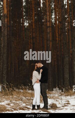 Young man and woman kissing in the winter forest. With the place for your text. Love, relationship, winter holidays. Winter couple photo ideas Stock Photo