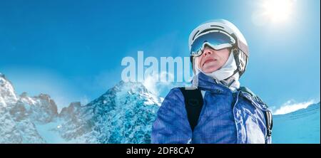 Skier female portrait in safe ski helmet and goggles with picturesque snowy Tatry mountains background. Active people winer vacation concept image. Stock Photo