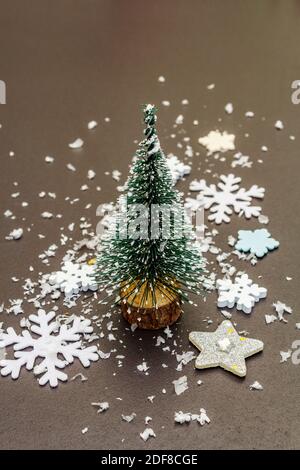 Small decorative Christmas trees with New Year's decor. Snowflakes and artificial snow on black stone concrete background, close up Stock Photo