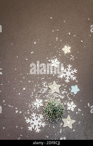 Small decorative Christmas trees with New Year's decor. Snowflakes and artificial snow on black stone concrete background, top view Stock Photo