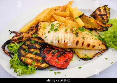 Grilled squid served with vegetables and fries. Traditional Greek dish.calamaris Stock Photo