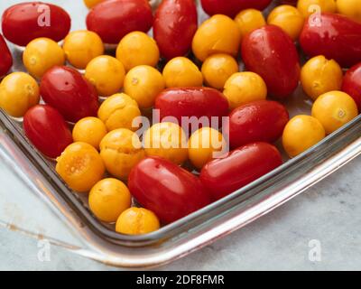 Cherry tomatoes and physalis in a baking dish before behing roasted.
