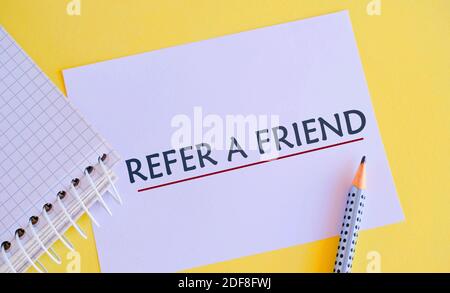 Handwriting text Refer A Friend. Concept meaning direct someone to another or send him something like gift, pencil, white paper with text REFER A FRIE Stock Photo