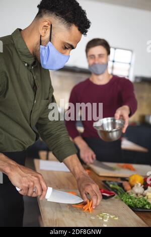Two diverse male chefs wearing face masks in kitchen Stock Photo