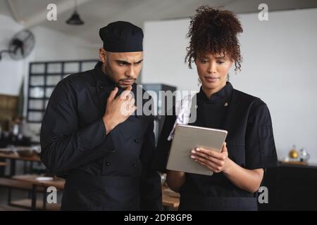 Two diverse male and female chefs in kitchen Stock Photo