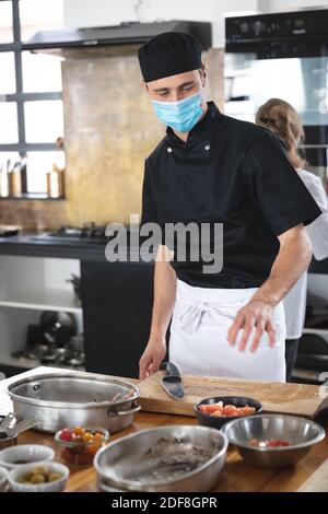 Caucasian male chef wearing face masks in kitchen Stock Photo
