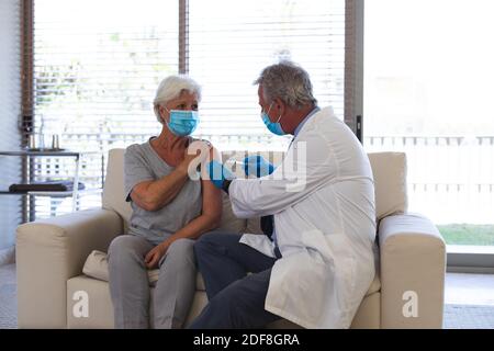 Caucasian male doctor giving covid19 vaccination to senior woman Stock Photo