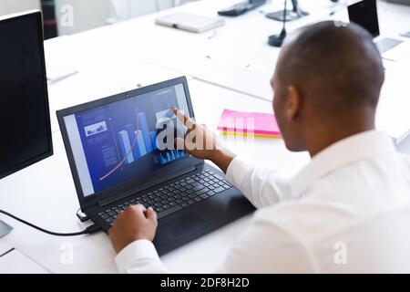 Mixed race man working in creative office, checking data on laptop Stock Photo