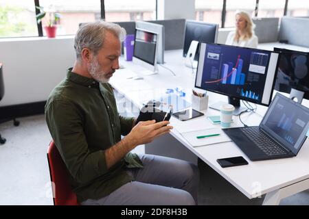 Caucasian man working in creative office, holding vr headset Stock Photo