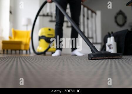 Man vacuuming the carpet in the room. House cleaning process Stock Photo