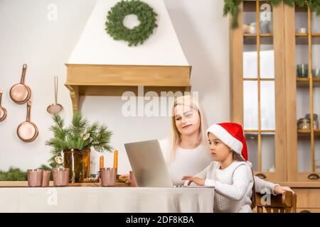 Asian mother and daughter using laptop Video Call Facetime Chatting Communication to father with decorating Christmas tree in white room at home Stock Photo