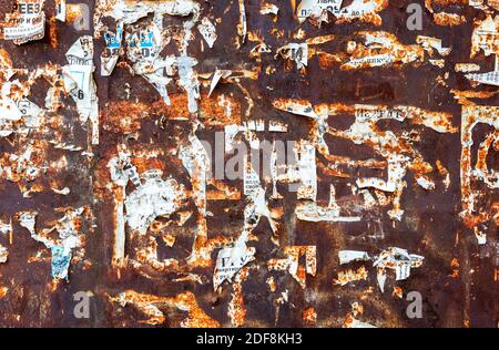 Old weathered grunge rusty metal texture with scraps of old paper as background Stock Photo