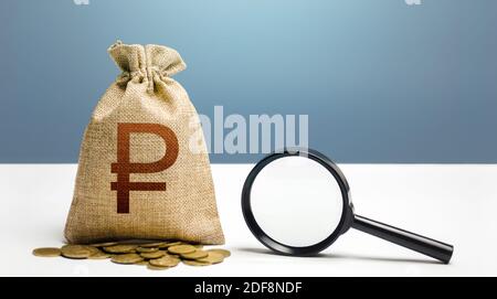 Russian ruble money bag and magnifying glass. Financial audit and monitoring of suspicious capital and transactions. Search for beneficiaries. Budget Stock Photo