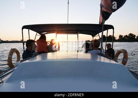 Friends travelling on yacht on calm sunset. Family Stock Photo