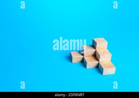 Wooden blocks pyramid on a blue background. Minimalism. Simple shapes geometry. Slide for presentation. Copy space, place for text. Steps. Stock Photo