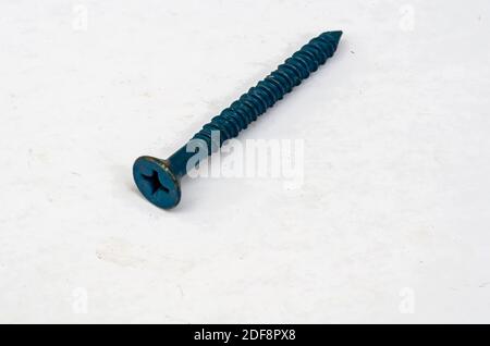 On a white background is a blue flat head screw with a cross slot for phillips screw, or cross cross-head screwdriver. Stock Photo