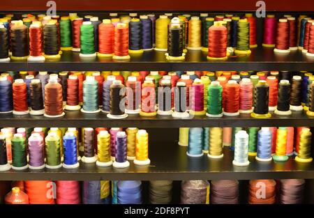Many different coloured cotton threads for sale in the window of a sewing and clothes repair shop in Beijing, China Stock Photo