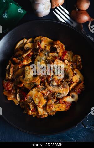 Cooked mushrooms with herbs and spices in black plate. Mushrooms saute. Stock Photo