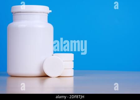 Big white tablets and medicine bottle on blue background.  Stock Photo