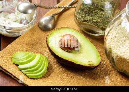 Fresh cutted avocado with sesame, soft cheese and herbs. Stock Photo