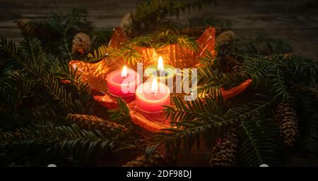 Christmas decoration with burning candles on dark background with branch with needles. Close-up and shallow depth of field. Christmas holidays and New Stock Photo