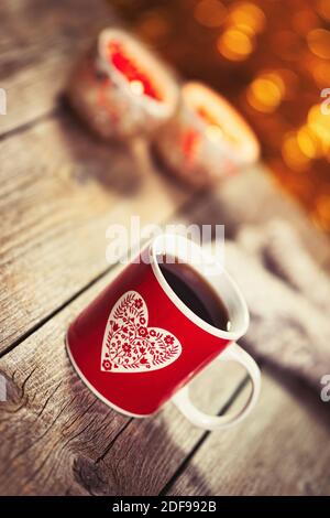 Homemade Christmas mulled wine punch on wooden rustic table. Burning candles, woolen gloves and blurred lights in background. Traditional autumn and w Stock Photo