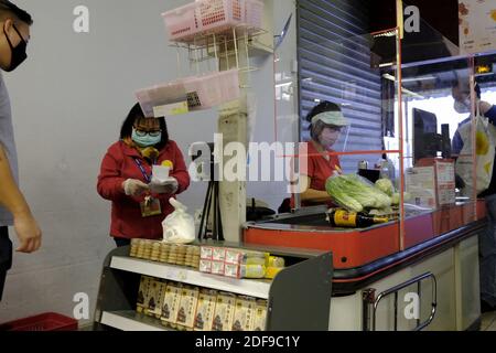 Supermarket cashier and customer wears face mask to protect from the coronavirus disease (COVID-19) in Paris, after the announcement by French President Emmanuel Macron of the strict home confinement rules of the French due to an outbreak of coronavirus pandemic (COVID-19) on March 18, 2020 in Paris, France. the French will have to stay at home, France has closed down all schools, theatres, cinemas and a range of shops, with only those selling food and other essential items allowed to remain open. under penalty of sanctions, prohibiting all but essential outings in a bid to curb the coronaviru Stock Photo