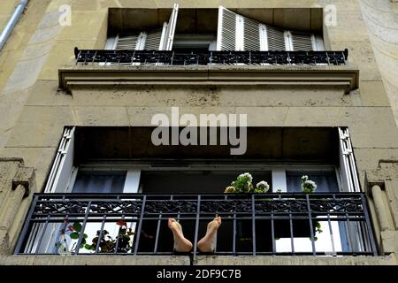 A confined Parisian enjoy sunny spring weather from a window ledge during lockdown imposed to slow the spreading of the coronavirus disease (COVID-19) in Paris. after the announcement by French President Emmanuel Macron of the strict home confinement rules of the French due to an outbreak of coronavirus pandemic (COVID-19) on March 18, 2020 in Paris, France. the French will have to stay at home, France has closed down all schools, theatres, cinemas and a range of shops, with only those selling food and other essential items allowed to remain open. under penalty of sanctions, prohibiting all bu Stock Photo