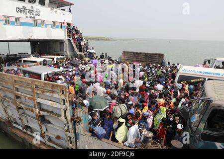 Bangladeshi garments workers try to get on board of a over crowed ferry as they returning to their village homes at the Shimulia ferry terminal in Mawa, near Dhaka, Bangladesh, April 05, 2020. Thousands of readymade garment workers from across the country had either walked or used alternative modes of transpiration to reach capital Dhaka over the past few days, as owners decided to open the factories amid a government-enforced soft shutdown to prevent the novel coronavirus from spreading further. But following harsh criticisms, BGMEA was forced to keep the factories closed until April 11. The Stock Photo