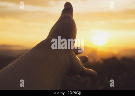 Hand against sunset view at dusk. Reaching out for help concept. Stock Photo