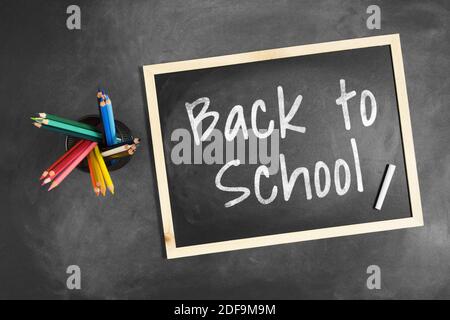 Back to School written on blackboard with multiple colorful colored pencil inside a pencil holder. Stock Photo