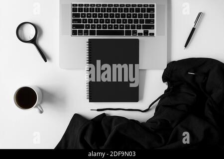 Notebook with copy space, sweater and laptop on white office table. Stock Photo