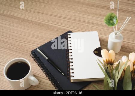 Spiral notebooks with coffee cup and flower on wood desk. Stock Photo