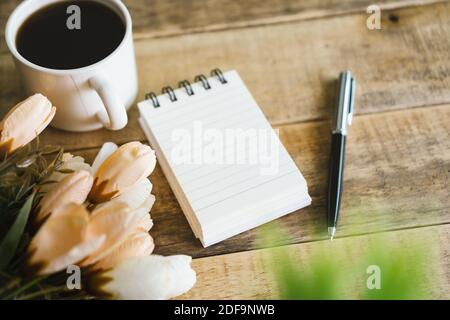 Small spiral notepad and coffee on rustic wood. Stock Photo