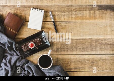 Small spiral notepad, butterscotch cake and cup of coffee on rustic wood. Flat lay. Stock Photo