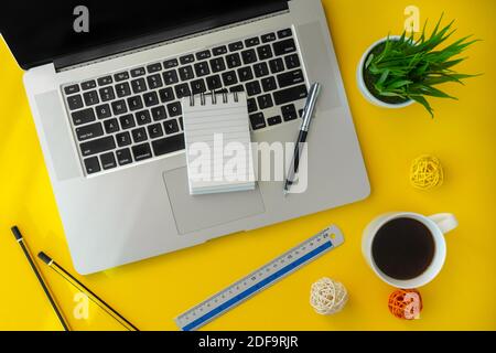 Laptop and small notebook on yellow working desk. Elegant workspace flat lay. Stock Photo