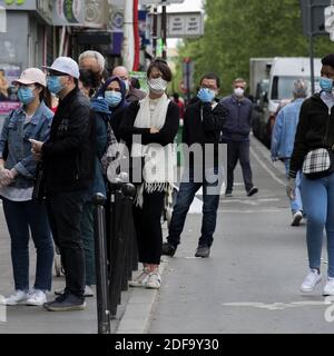 Confined Parisians wearing a protective surgical face masks against coronavirus disease Queue in front of a supermarket in Paris. after the announcement by French President Emmanuel Macron of the strict home confinement rules of the French due to an outbreak of coronavirus pandemic (COVID-19) on March 18, 2020 in Paris, France. the French will have to stay at home, France has closed down all schools, theatres, cinemas and a range of shops, with only those selling food and other essential items allowed to remain open. under penalty of sanctions, prohibiting all but essential outings in a bid to Stock Photo