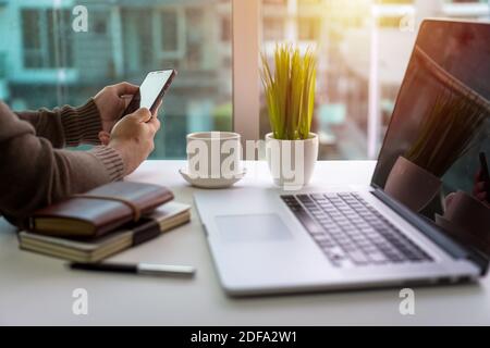 Holding and using smart phone. Freelance lifestyle home office. Stock Photo