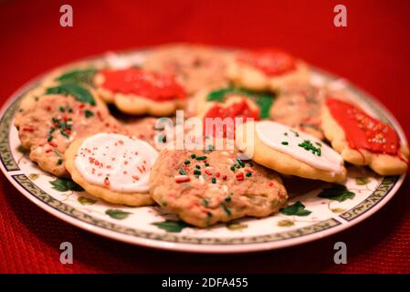 Fresh, homemade Christmas cookies set out for Santa. Sugar cookies with sprinkles and icing by the fireplace and the Christmas tree. Time to decorate Stock Photo
