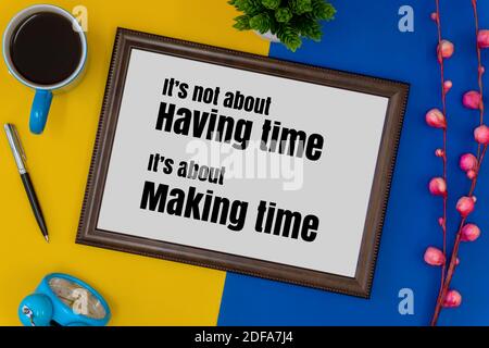 Wood frame, clock and coffee mug on blue and yellow background. Inspirational quote. Stock Photo