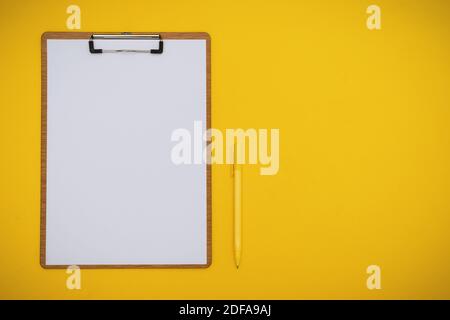 Overhead View of Paper on Clipboard and Pen on Yellow Background