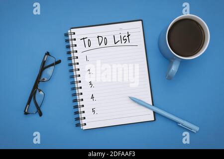 Overhead View of To Do List on Notebook over Pastel Blue Background Stock Photo
