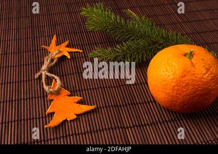 New Year Concept. Christmas decorations hand made from tangerine peel, fir-tree branches and the fruits of mandarin orange on bamboo mat background Stock Photo