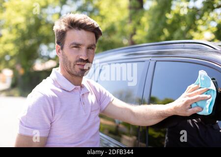 young man cleaning his car outdoors Stock Photo
