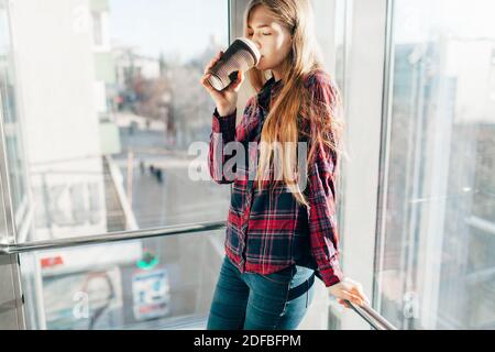 young beautiful girl drinking coffee, a woman in an office building, the bright sun Stock Photo